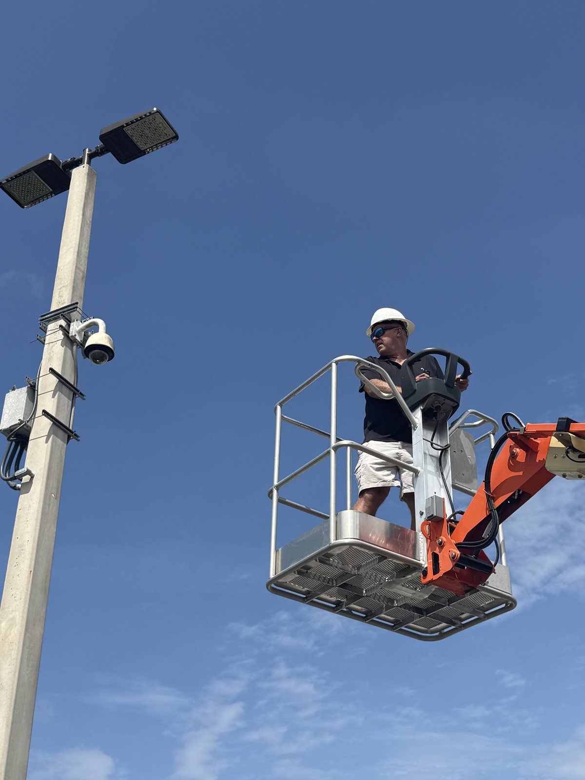 Assessing a pole mounted security camera and lighting placement from a boom lift, part of a crime prevention through environmental design survey