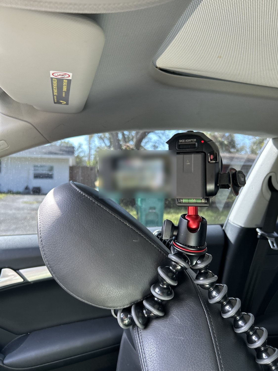 A 4K camcorder mounted on a flexible tripod inside a vehicle, positioned to record through the windscreen during a surveillance assignment