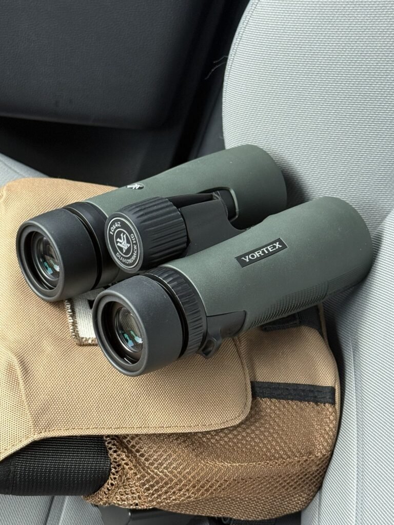 Vortex 10x42 binoculars on a surveillance kit bag inside a Florida private investigator's vehicle